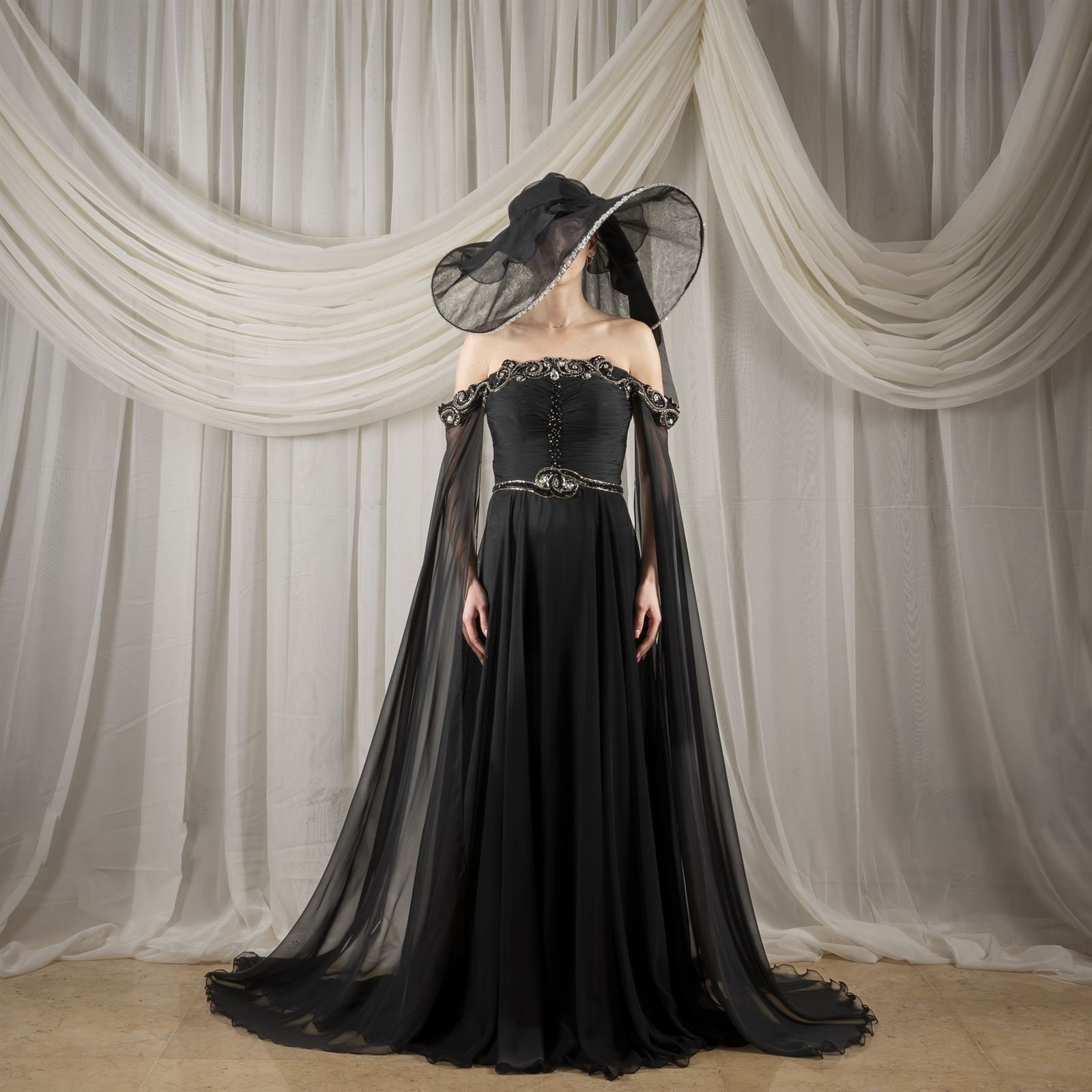 Black gown with sculpted hat against draped curtains