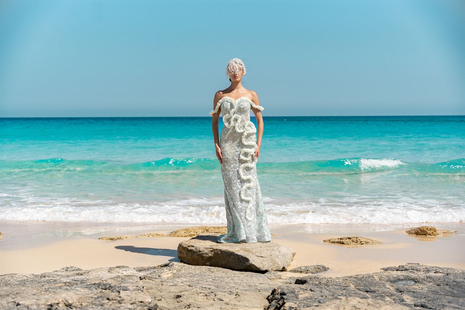 Sculpted white gown on a rock against a turquoise sea