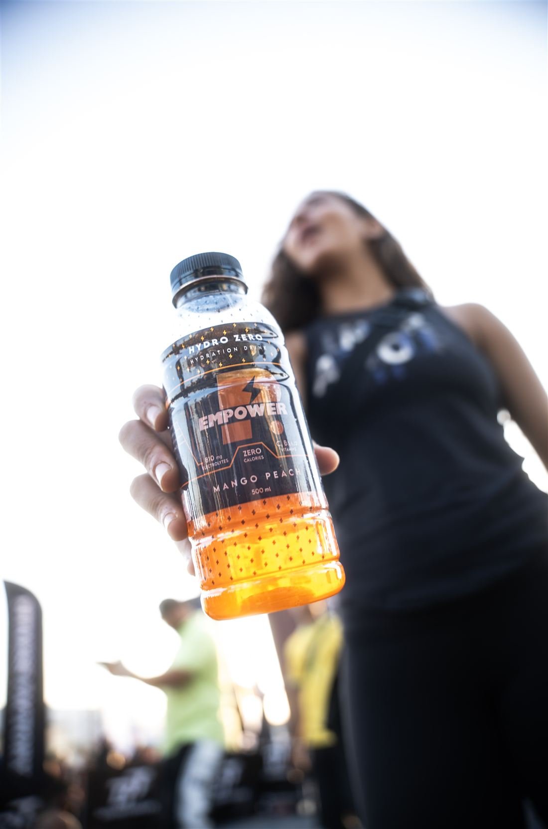 Athlete holding a Mango Peach bottle toward the camera